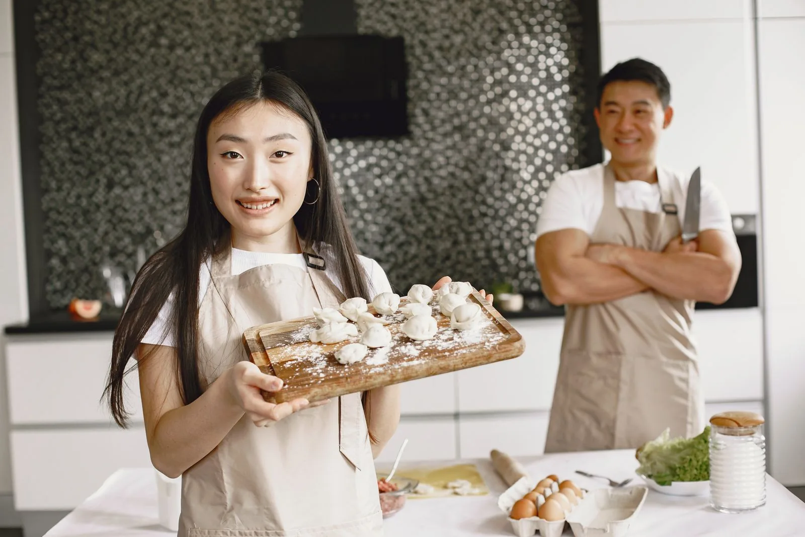 Two bakers smiling proudly with food they made together in a bright kitchen