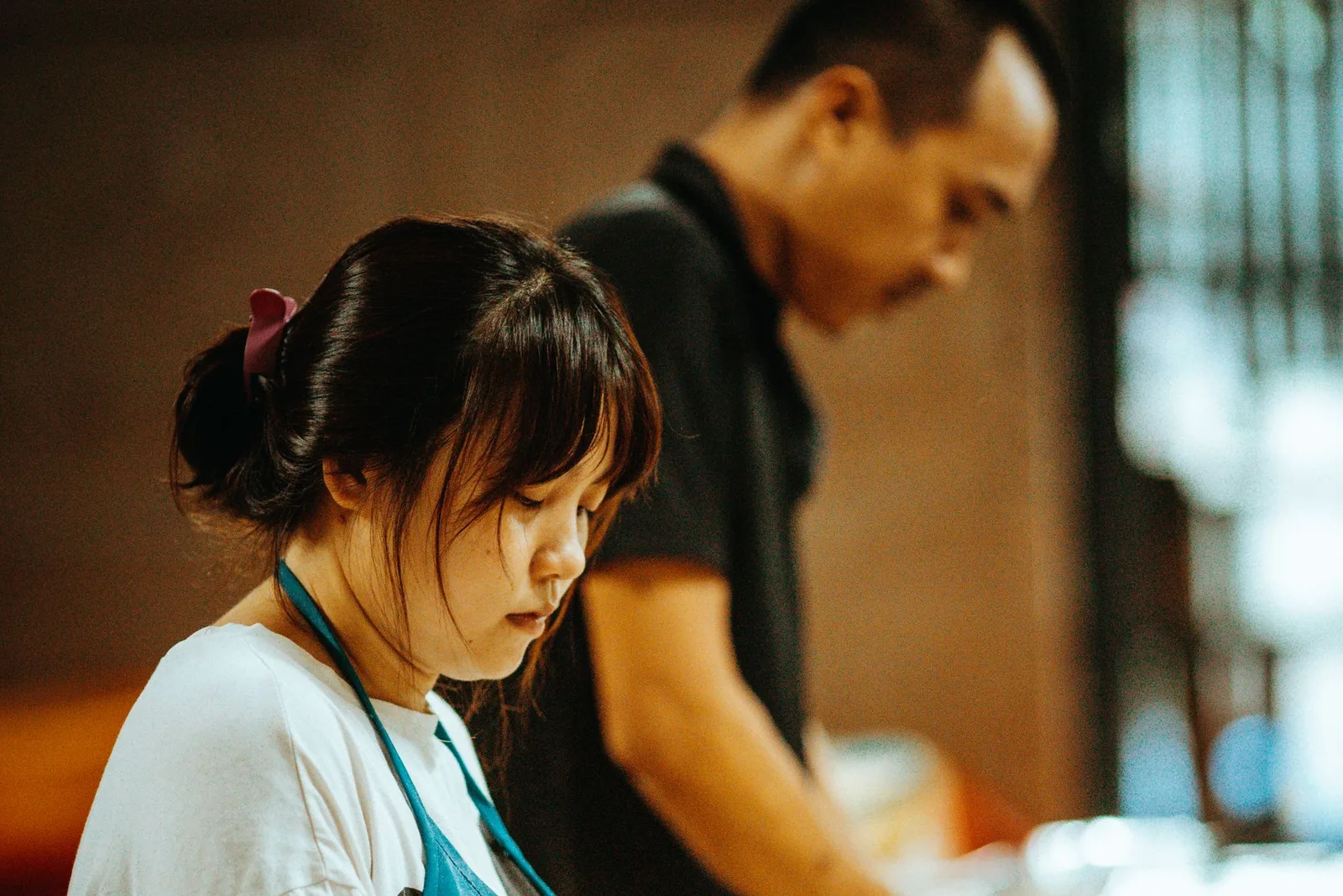 Two young bakers working together, shaping dough at a kitchen counter