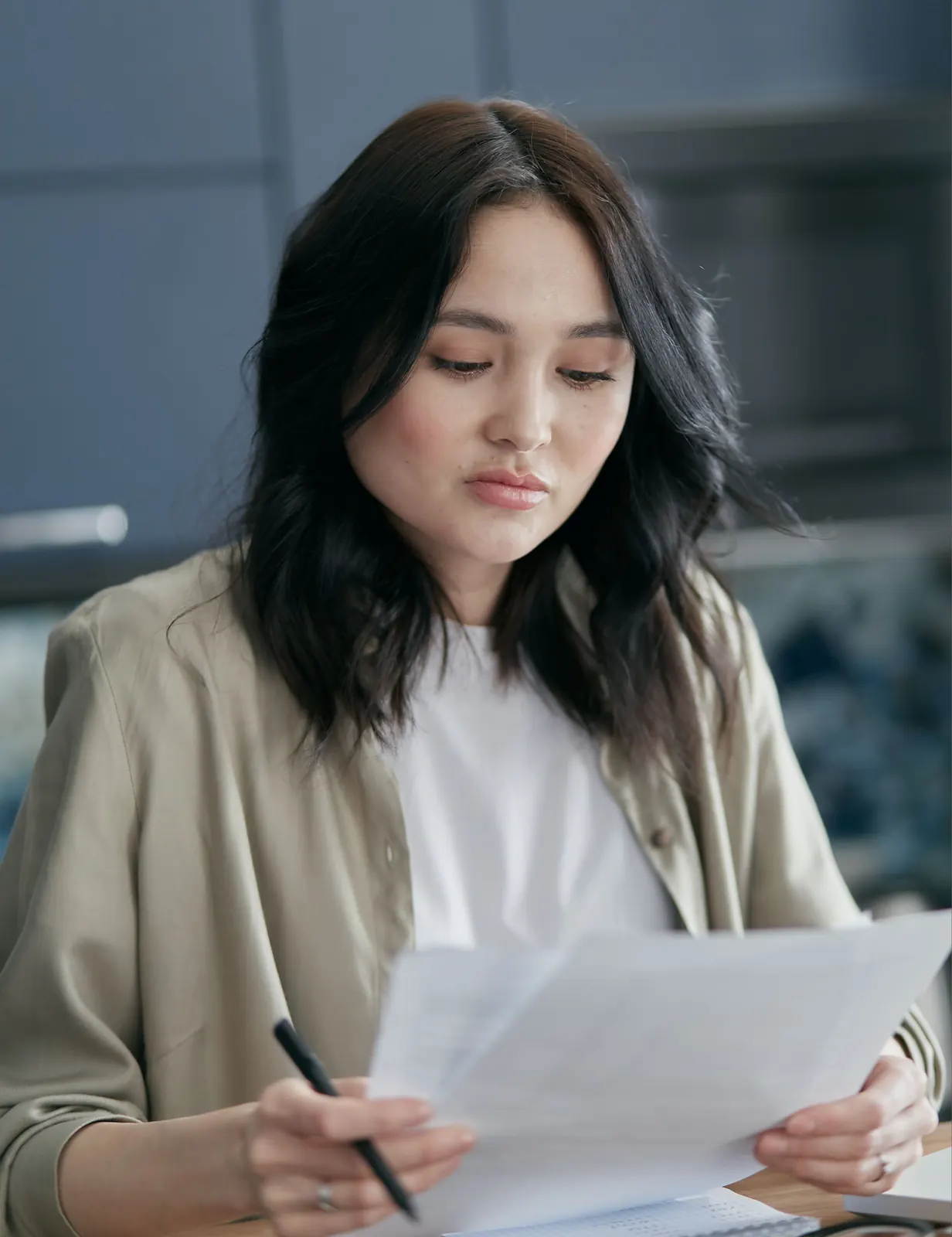 Focused young woman reviewing business paperwork, pen in hand