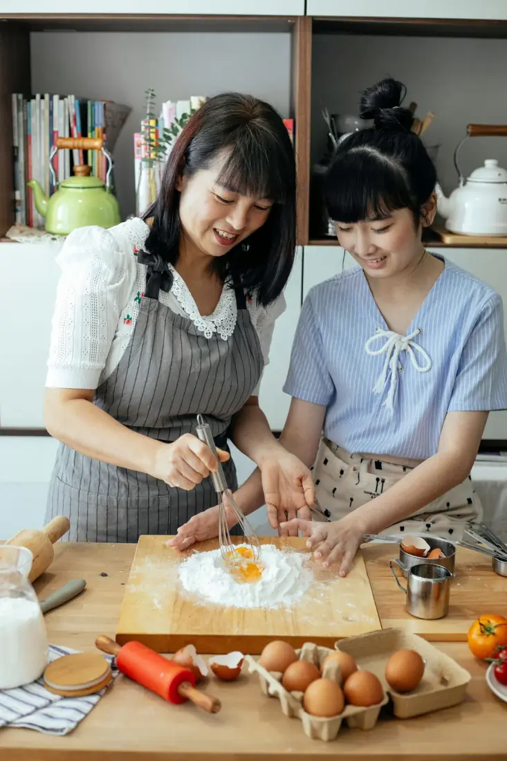 两位学员在实作烘焙课程中一起将鸡蛋打入面粉中搅拌