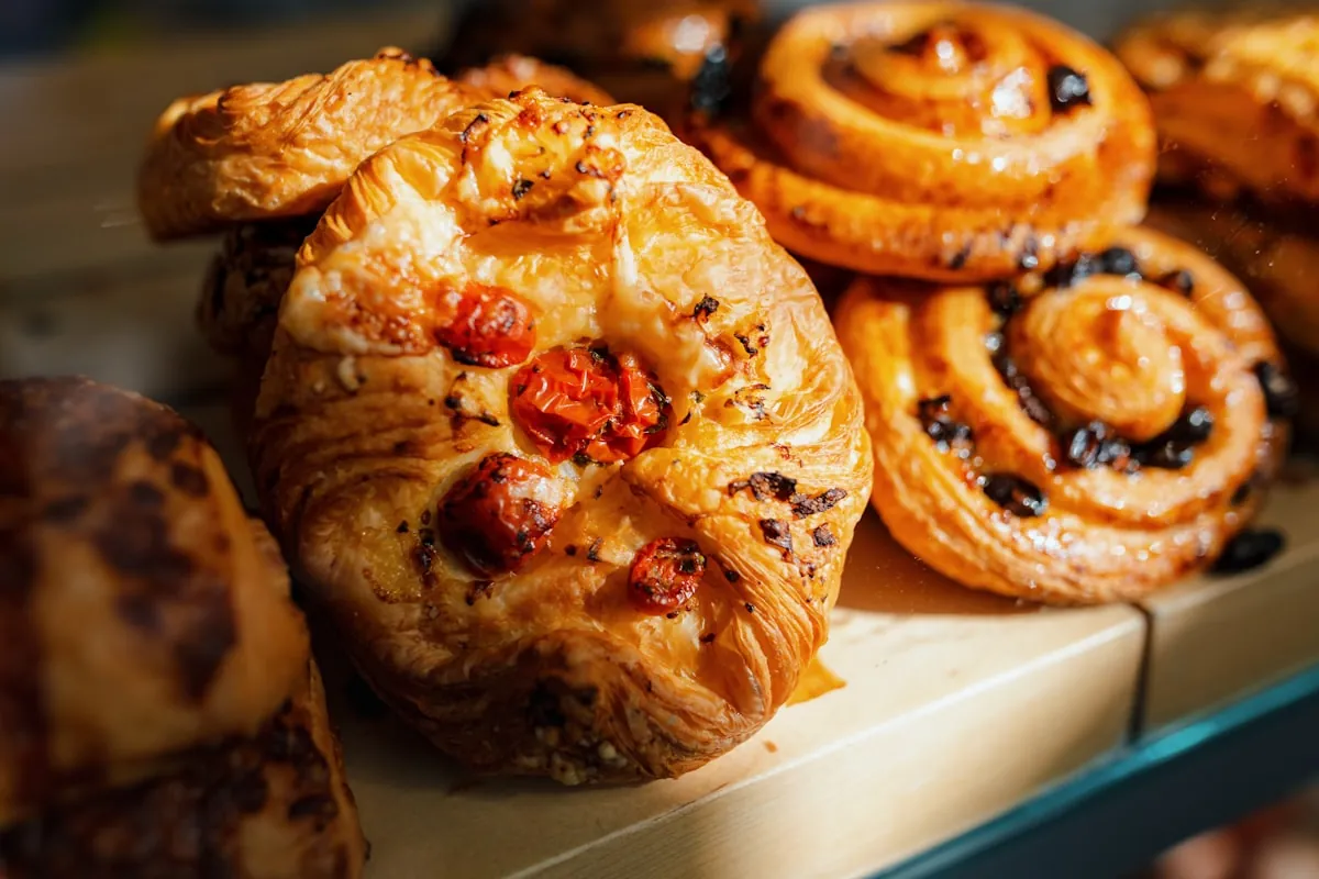 Close-up display of golden baked pastries and glazed swirl buns on a bakery counter