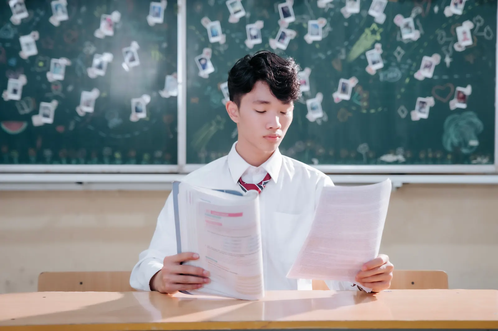 Student in a classroom carefully reading through his exam papers