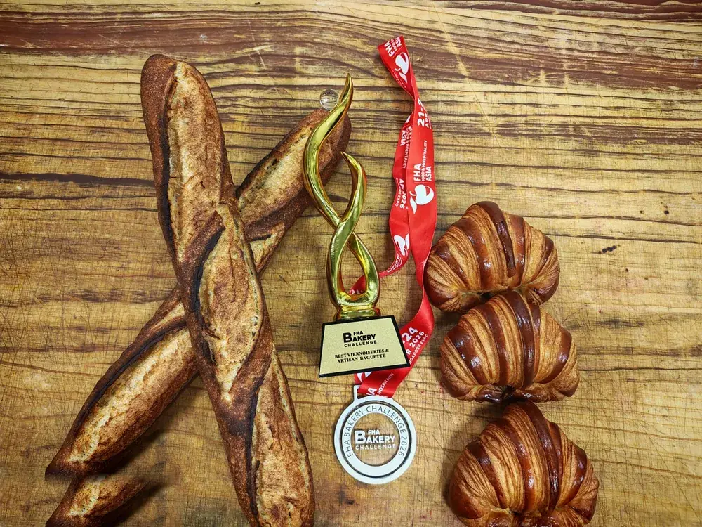 FHA Bakery Challenge 2026 trophy and medal for Best Viennoiseries & Artisan Baguette beside Chef Terry's sourdough baguettes and croissants